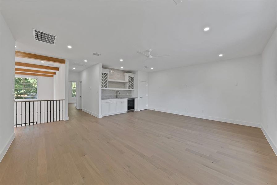 Spacious room with light wood-finish flooring, recessed lighting, and a ceiling fan