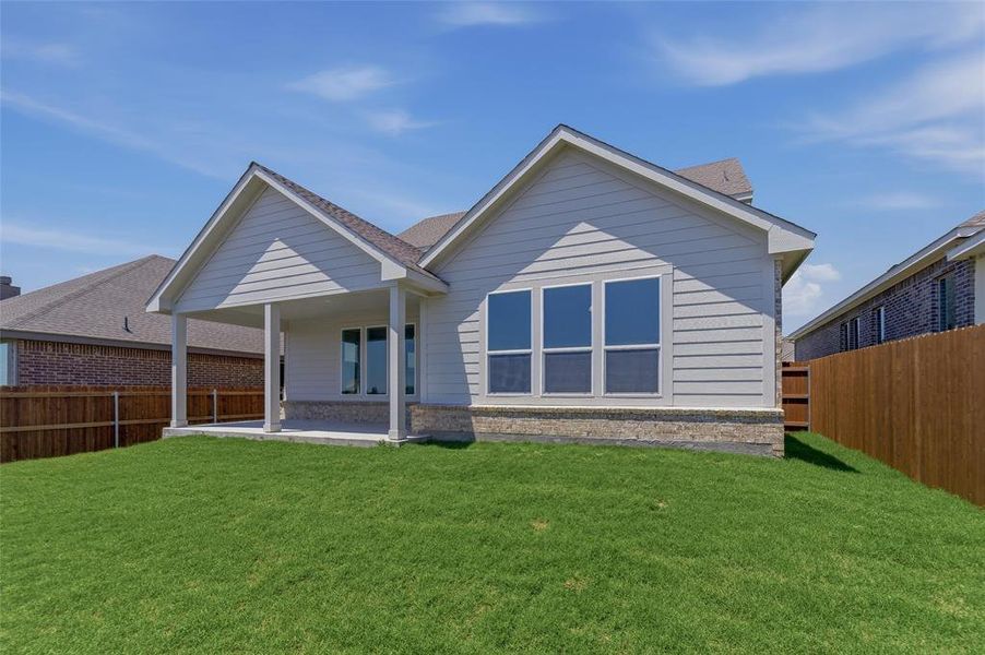 Expansive grassy yard leading to a covered patio with columns