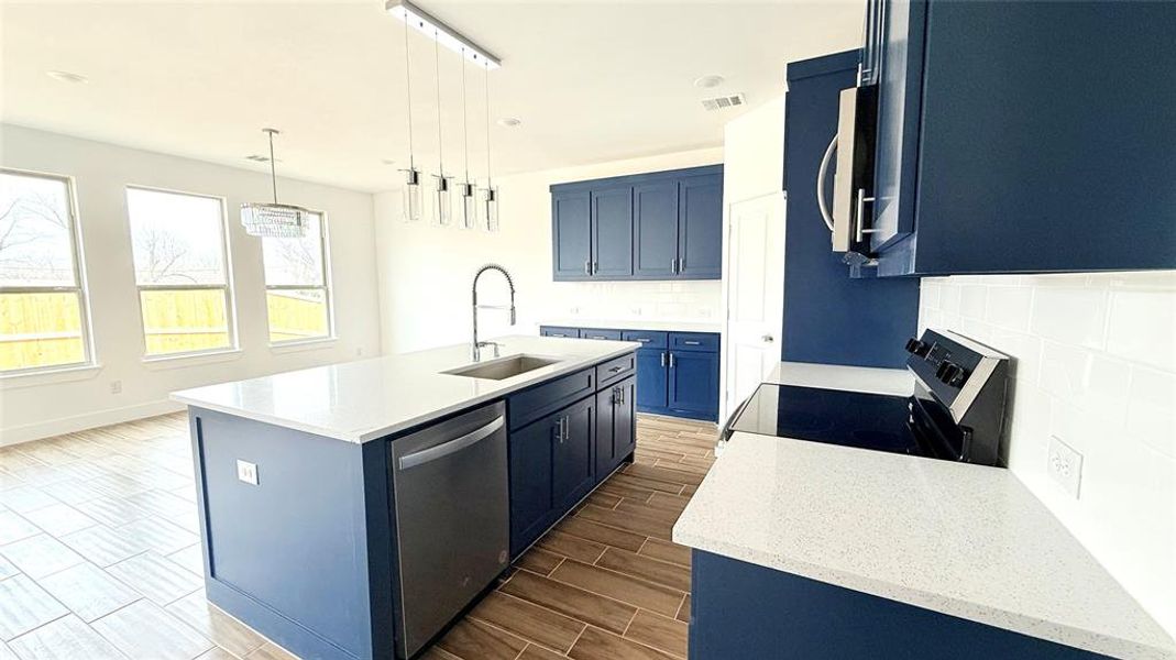 Kitchen featuring white microwave, blue cabinetry, dishwasher, electric range, and a sink