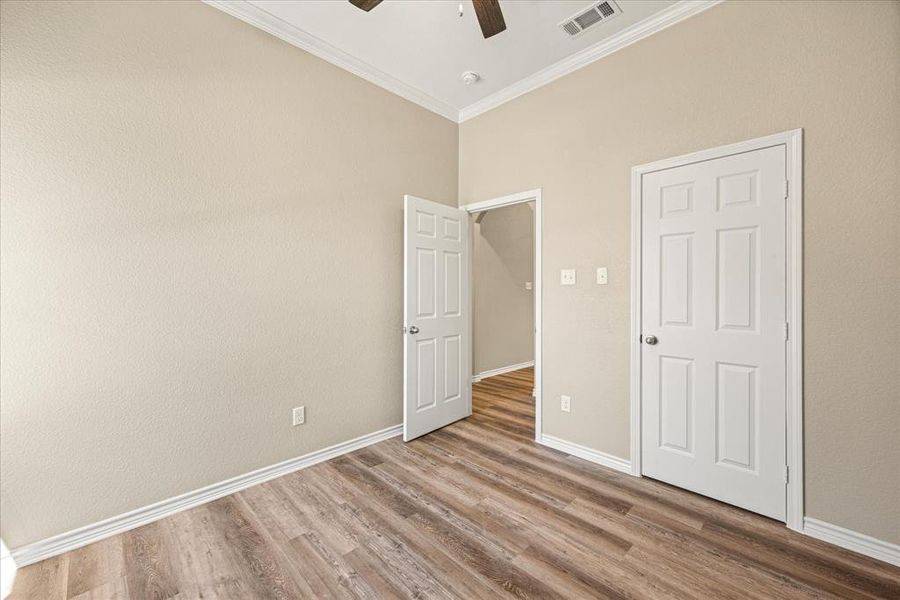 Unfurnished bedroom featuring light wood-style floors, crown molding, and a ceiling fan
