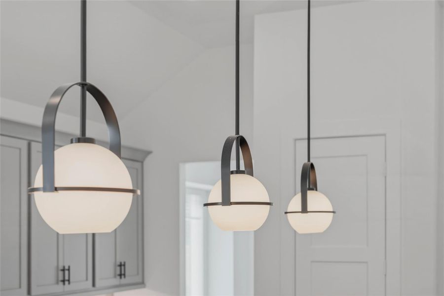 A trio of contemporary globe pendant lights perfectly illuminates the clean lines of the oversized gourmet prep island. A trio of contemporary globe pendant lights perfectly illuminates the clean lines of the oversized gourmet prep island.