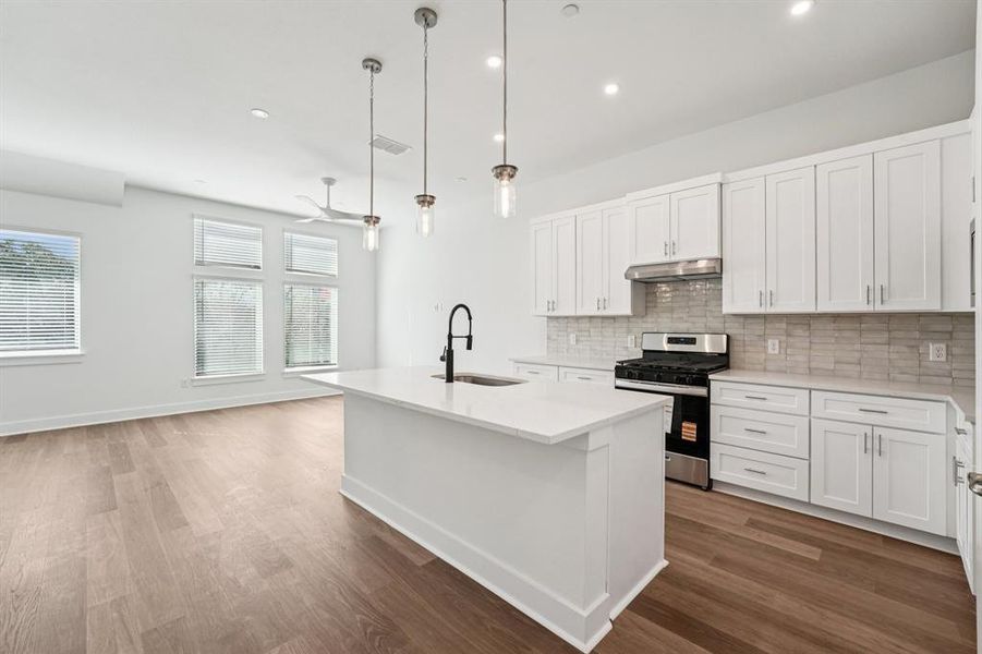 The kitchen is the heart of the living space, featuring a large quartz island and stylish pendant lights hanging above. (Sample photo of finishes and layout)
