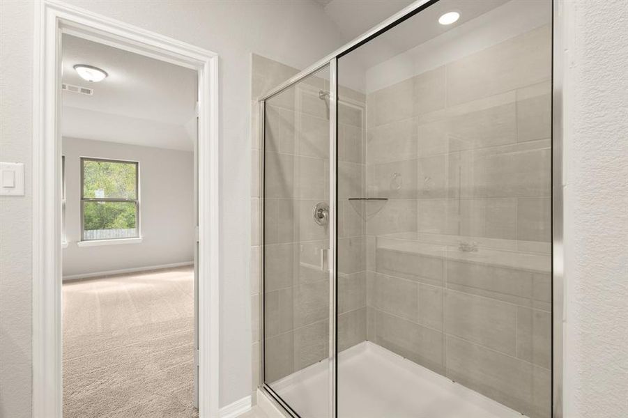 This additional view of your primary bathroom features tile flooring, fresh paint, walk-in shower, and a large walk-in closet.