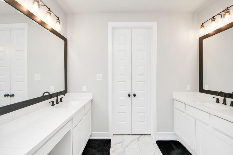 Owner’s bath offers dual vanities with quartz countertops and modern matte-black fixtures.
