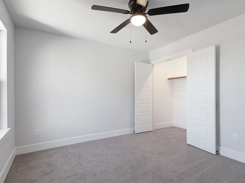 Unfurnished bedroom with ceiling fan and light carpet