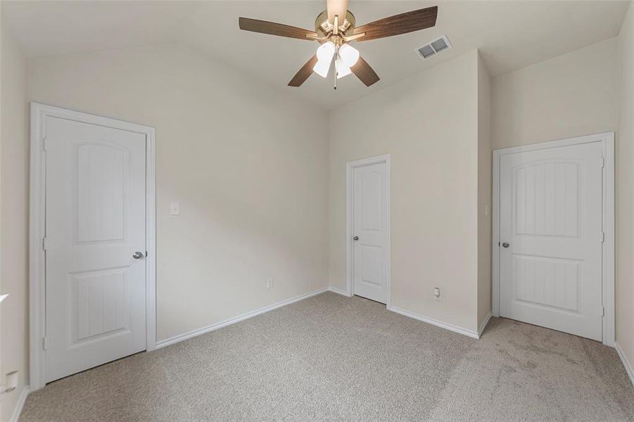 Unfurnished bedroom with vaulted ceiling, carpet flooring, baseboards, and a ceiling fan Unfurnished bedroom with vaulted ceiling, carpet flooring, baseboards, and a ceiling fan