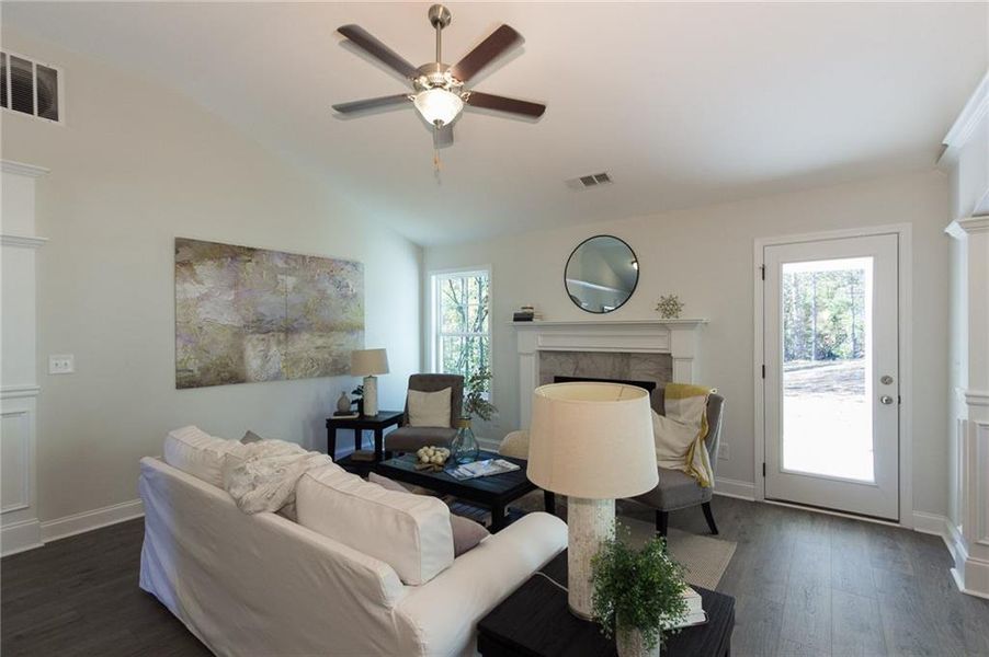 Living room featuring dark wood-type flooring, a wealth of natural light, a fireplace, and lofted ceiling