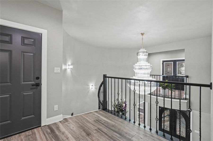 Corridor with wood finished floors and a chandelier