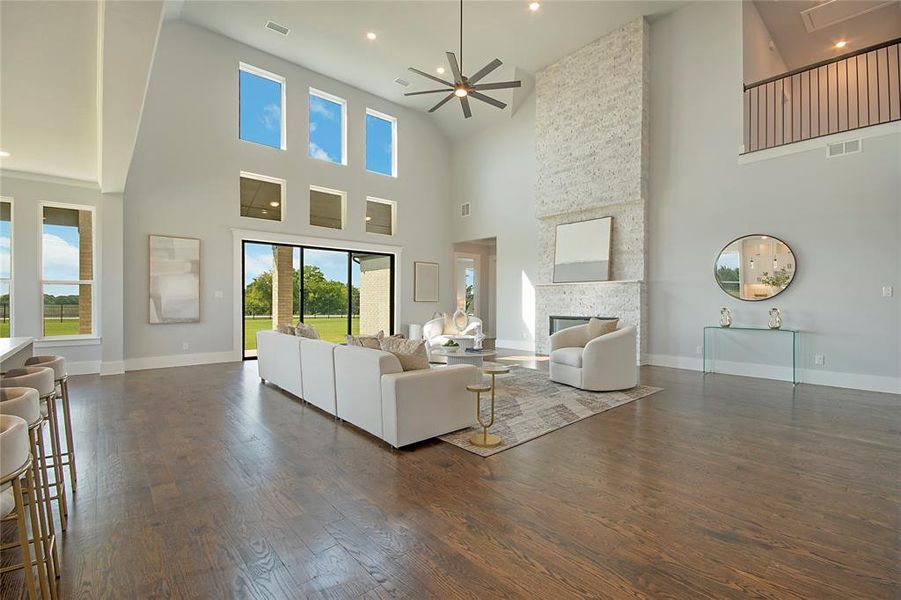 Living area with a stone fireplace, dark wood finished floors, a ceiling fan, recessed lighting, and a towering ceiling Living area with a stone fireplace, dark wood finished floors, a ceiling fan, recessed lighting, and a towering ceiling