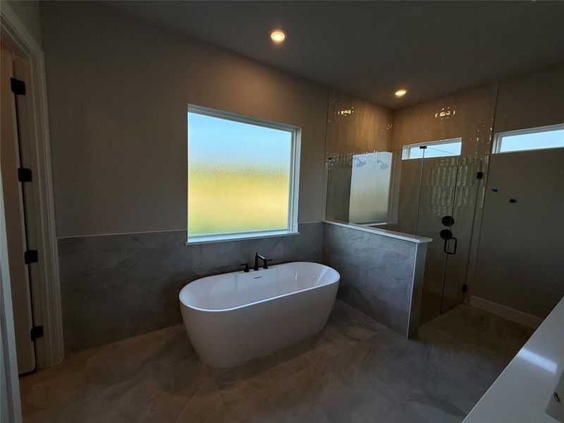Bathroom with tile walls, a soaking tub, a shower stall, recessed lighting, and wainscoting