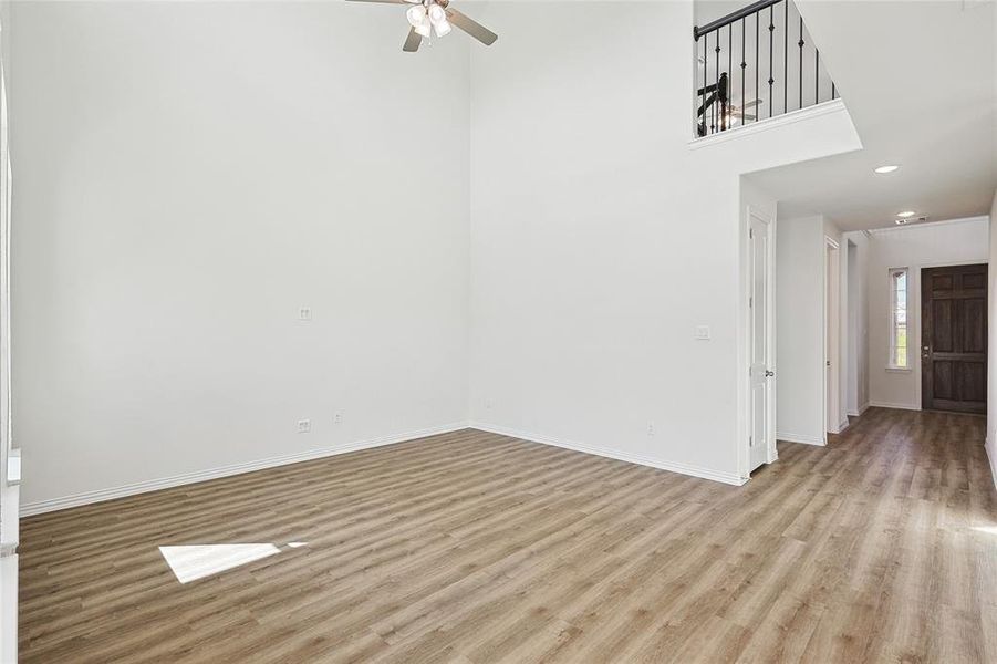 Empty room with a towering ceiling, ceiling fan, and light hardwood / wood-style floors