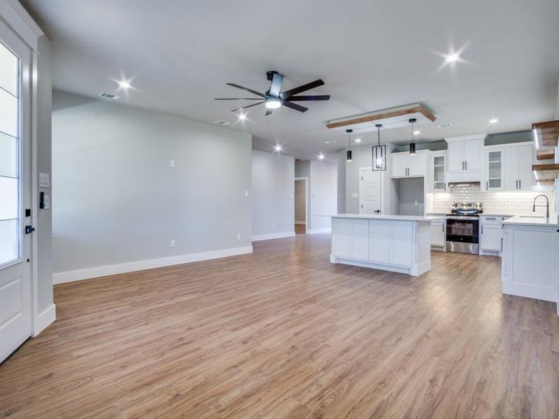 Unfurnished living room with light hardwood / wood-style floors, ceiling fan, and sink