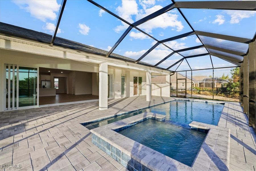 View of pool featuring a sunroom, a pool with connected hot tub, a patio, and a lanai