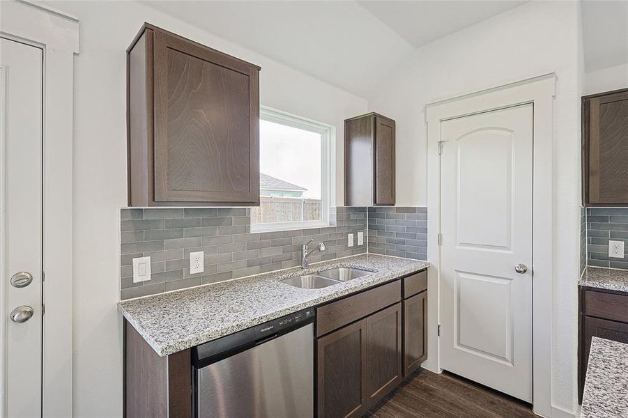 Kitchen featuring light stone countertops, sink, backsplash, stainless steel dishwasher, and dark hardwood / wood-style floors