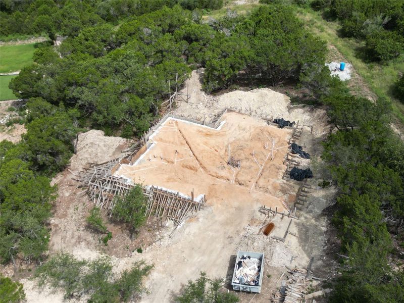 Witness the early stages of a custom home taking shape amidst a verdant, private landscape.