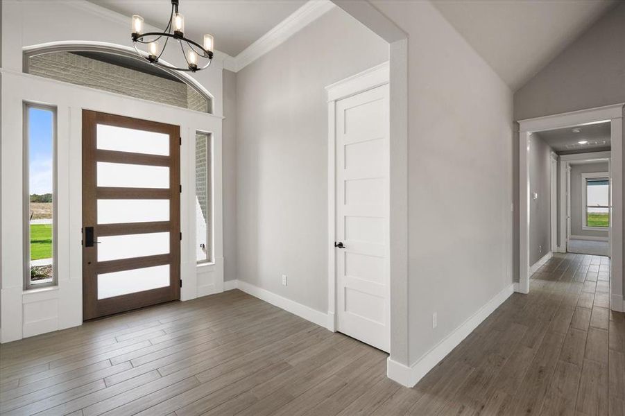 Foyer entrance featuring ornamental molding, lofted ceiling, an inviting chandelier, and dark hardwood / wood-style flooring