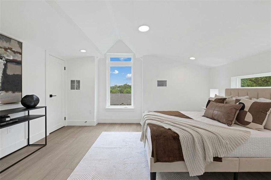 Bedroom with light wood finished floors, vaulted ceiling, and recessed lighting