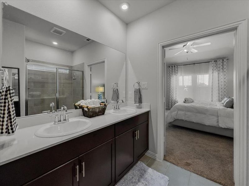 Bathroom with an enclosed shower, ceiling fan, tile patterned floors, and double sink vanity