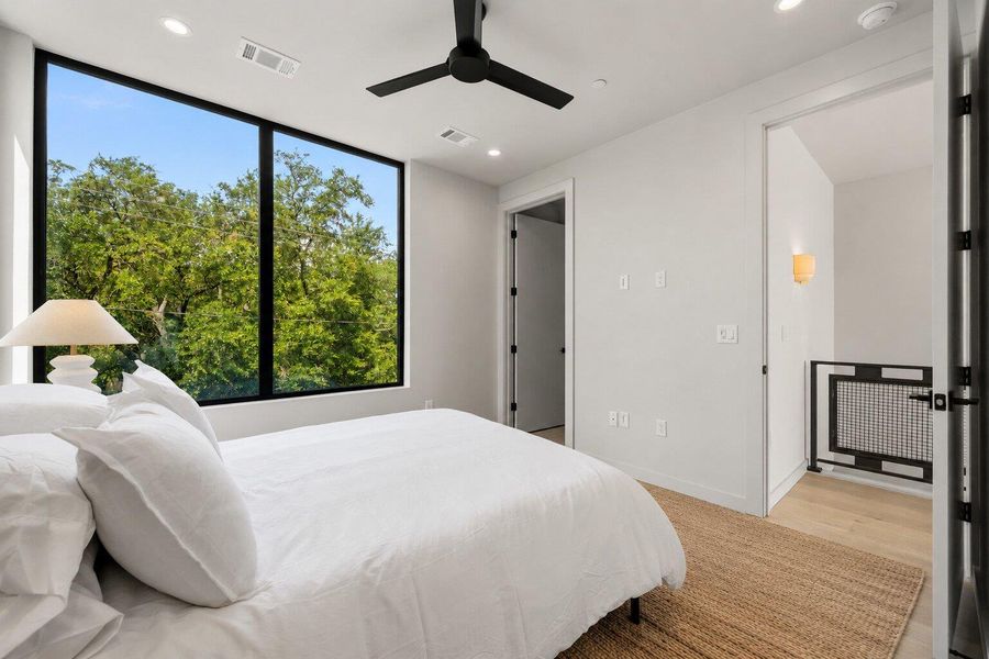 Floor-to-ceiling windows illuminate this tranquil bedroom with treetop views. Floor-to-ceiling windows illuminate this tranquil bedroom with treetop views.