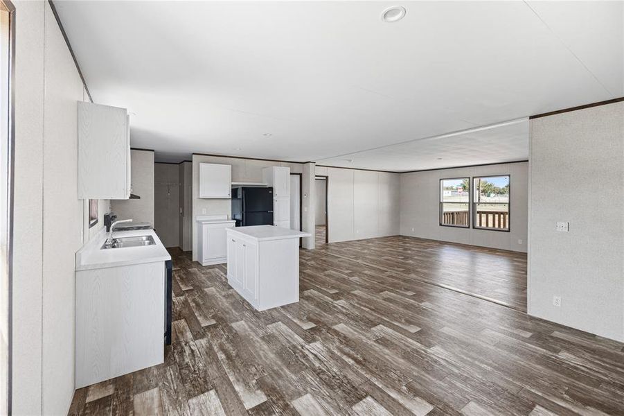 Kitchen featuring sink, black refrigerator, white cabinetry, and dark hardwood / wood-style floors