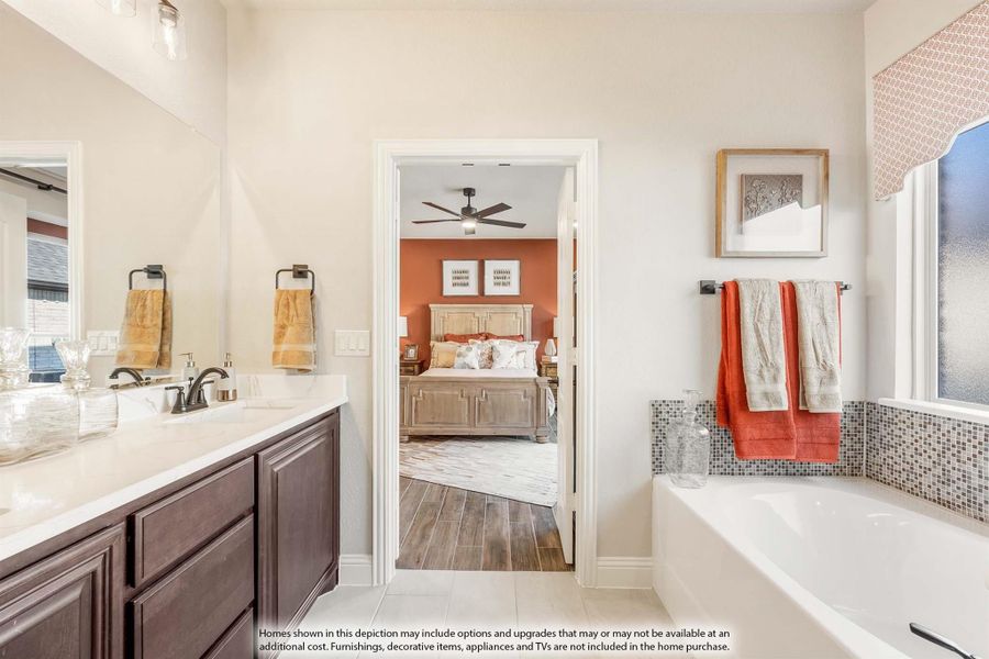 Master bathroom with double vanity, soaking tub, and open view into bedroom with ceiling fan Master bathroom with double vanity, soaking tub, and open view into bedroom with ceiling fan
