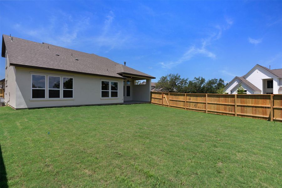 Spacious backyard featuring a manicured lawn and privacy fencing