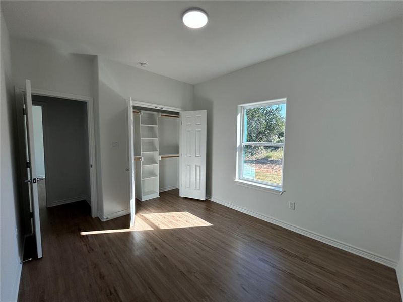 Bedroom with dark wood-type flooring and a closet