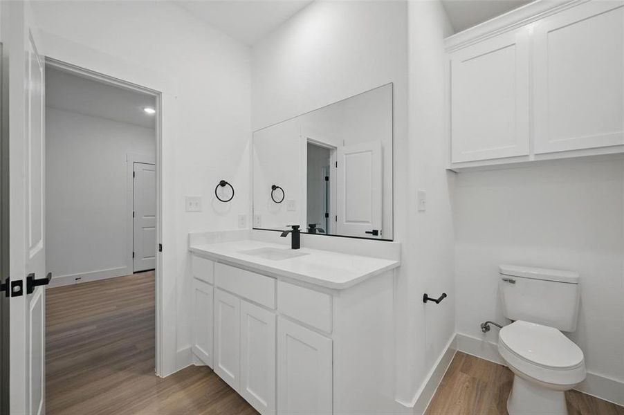 Bathroom with wood finished floors, vanity, toilet, and baseboards