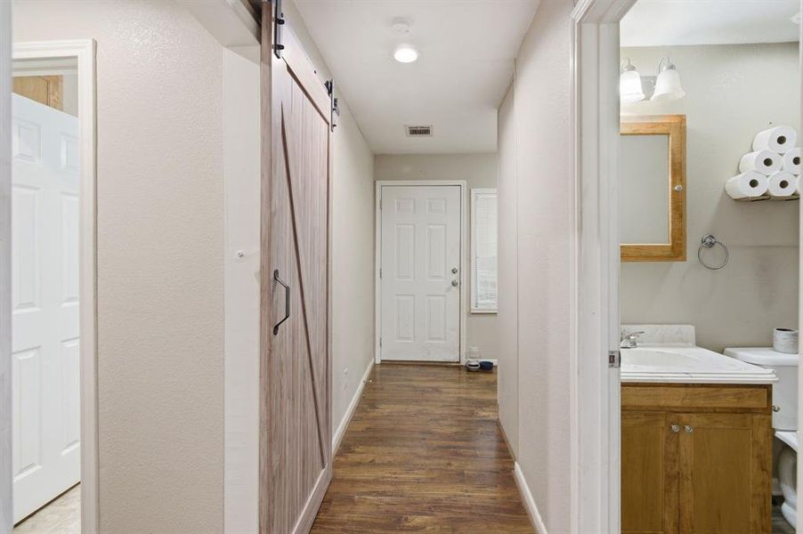 Hallway with wood-finish flooring, a contemporary barn door, and a recessed ceiling light