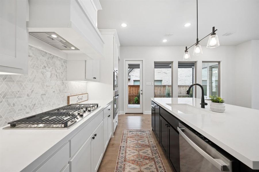 Contemporary kitchen featuring white cabinetry, a built-in gas range with a decorative range hood, and designer tile backsplash