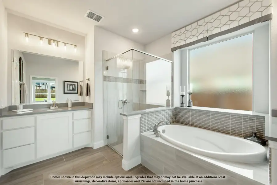 Master bathroom with soaking tub, glass walk-in shower, double vanity, and gray tile accents.