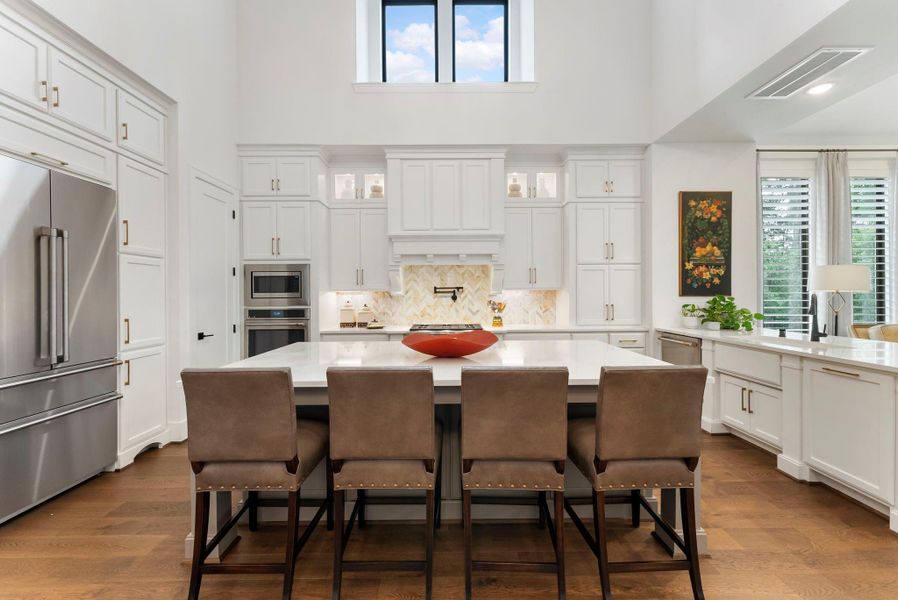 The kitchen’s oversized island anchors the open plan and offers generous space for prep, serving, and gathering. Upgraded lighting, cabinetry, and storage selections create a more custom feel than a standard builder finish.