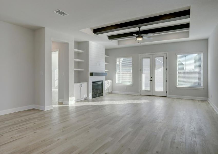 Expansive living room with a fireplace, floating shelves, and large windows.