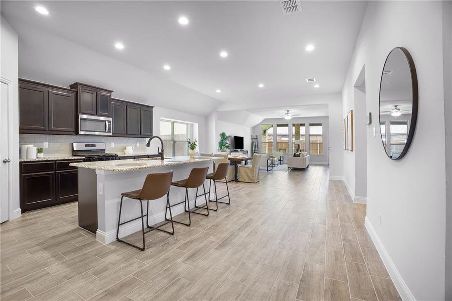 Kitchen featuring a ceiling fan, lofted ceiling, recessed lighting, decorative backsplash, and open floor plan
