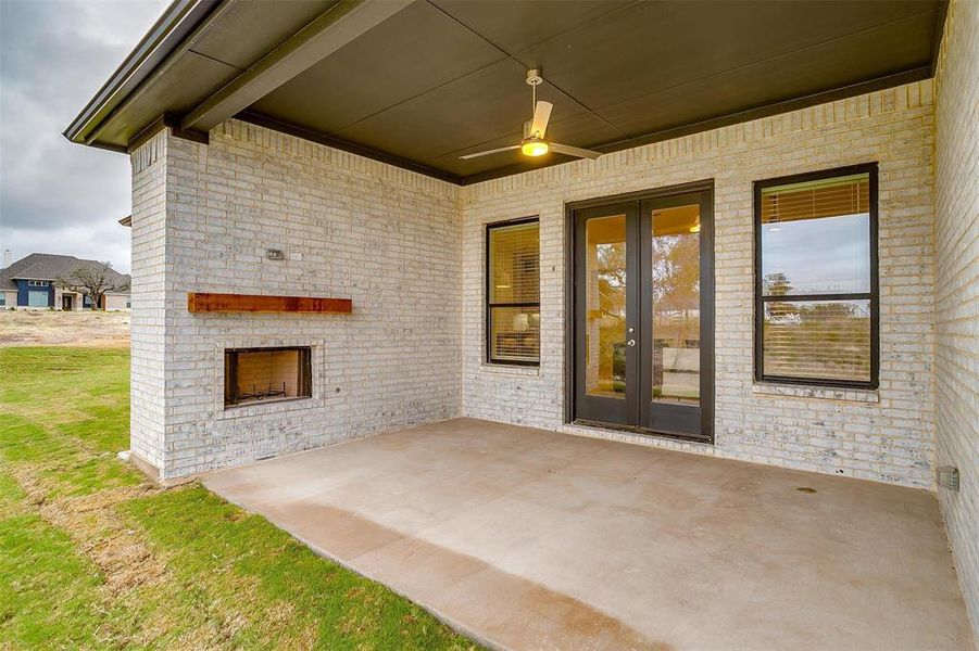 Back of house featuring a covered patio with fireplace and french doors that open into living area