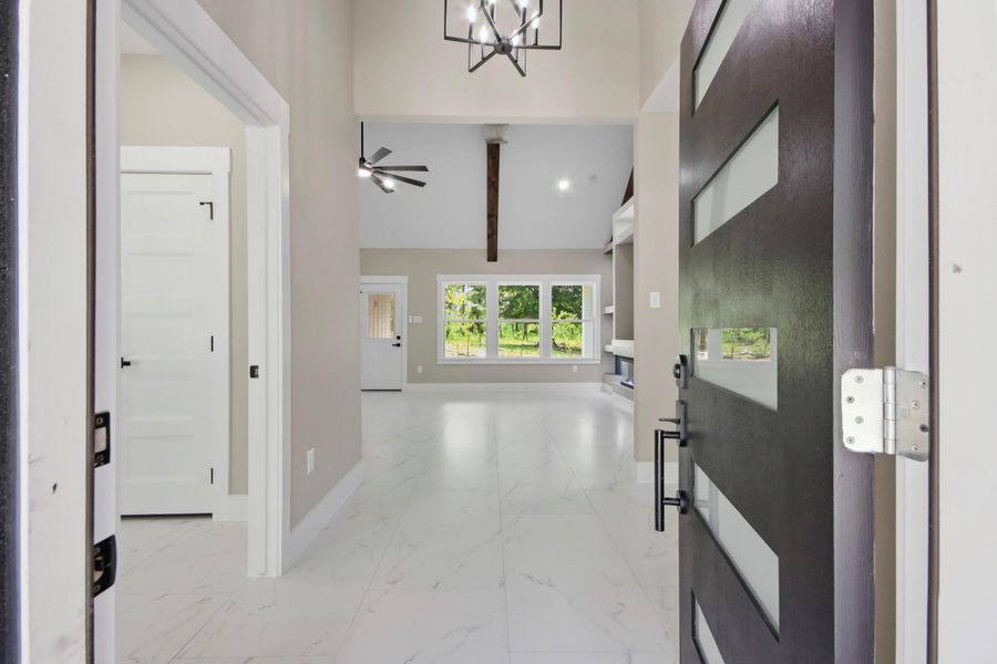 Step through the modern glass-paneled entry door into a bright, airy foyer with soaring vertical volume. Large premium tile flooring draws you into a stunning great room anchored by a dramatic vaulted ceiling and a rustic ridge beam. Step through the modern glass-paneled entry door into a bright, airy foyer with soaring vertical volume. Large premium tile flooring draws you into a stunning great room anchored by a dramatic vaulted ceiling and a rustic ridge beam.