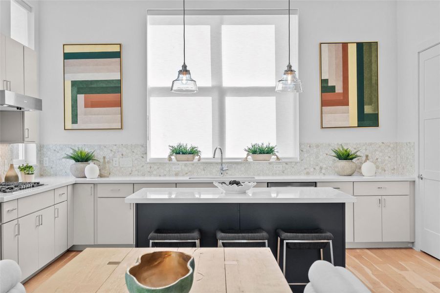 Contemporary kitchen featuring a central island with seating, light wood-finish flooring, white cabinetry, integrated stainless steel appliances, and a mosaic tile backsplash
