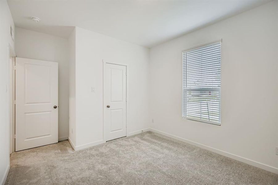 Unfurnished bedroom featuring light carpet and baseboards