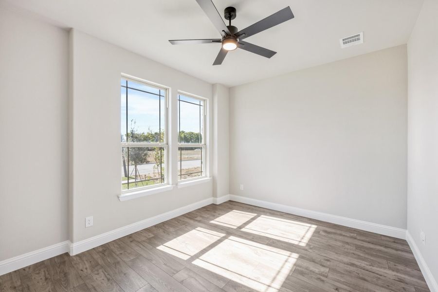 Empty bedroom with hardwood floors, ceiling fan, and two windows with natural light Empty bedroom with hardwood floors, ceiling fan, and two windows with natural light