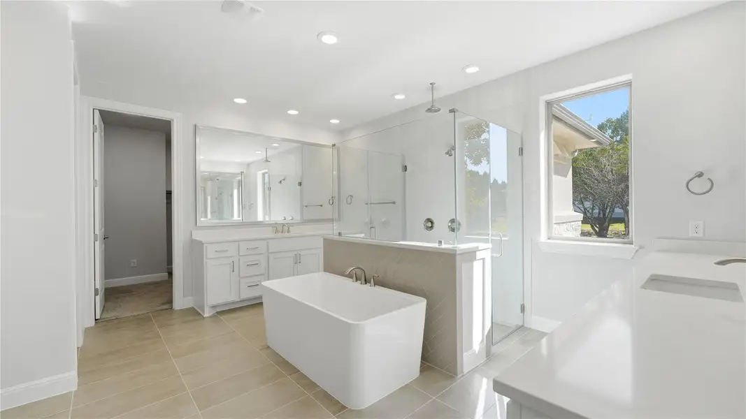 Bathroom featuring a freestanding tub, vanity, a shower stall, light tile patterned floors, and recessed lighting Bathroom featuring a freestanding tub, vanity, a shower stall, light tile patterned floors, and recessed lighting