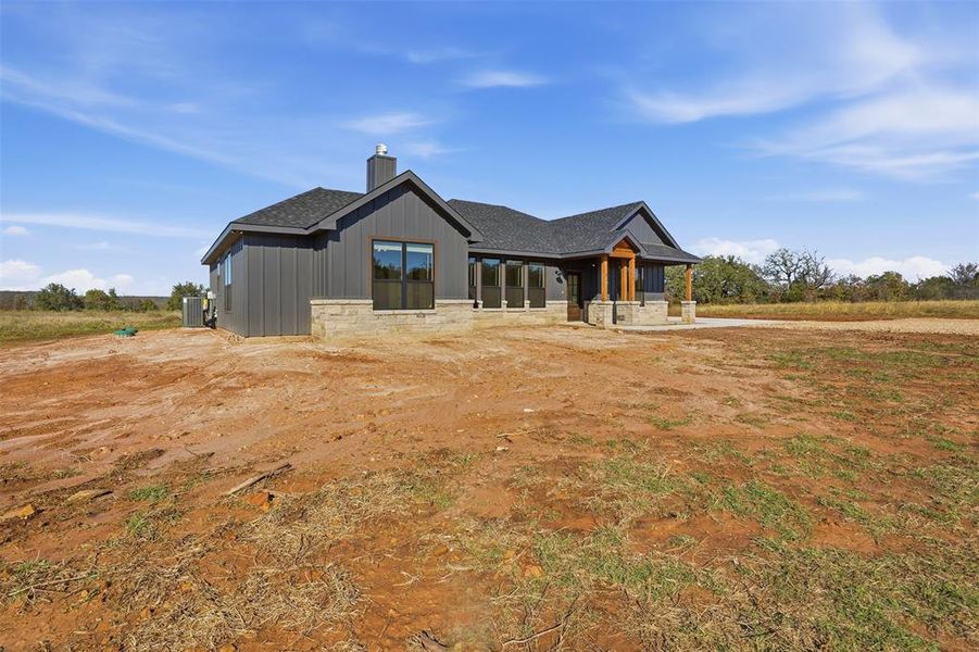 View of front of home with covered porch, a chimney, roof with shingles, and stone siding View of front of home with covered porch, a chimney, roof with shingles, and stone siding