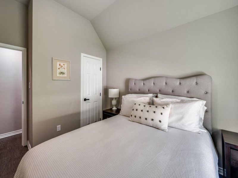 Bedroom with vaulted ceiling, carpet flooring, and baseboards Bedroom with vaulted ceiling, carpet flooring, and baseboards