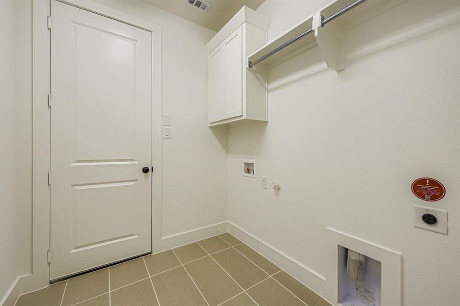 Washroom with hookup for a gas dryer, light tile patterned floors, hookup for a washing machine, cabinet space, and electric dryer hookup Washroom with hookup for a gas dryer, light tile patterned floors, hookup for a washing machine, cabinet space, and electric dryer hookup