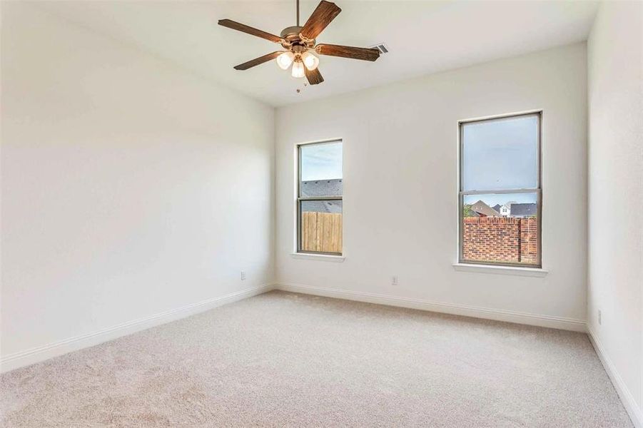 Carpeted empty room featuring baseboards and ceiling fan Carpeted empty room featuring baseboards and ceiling fan