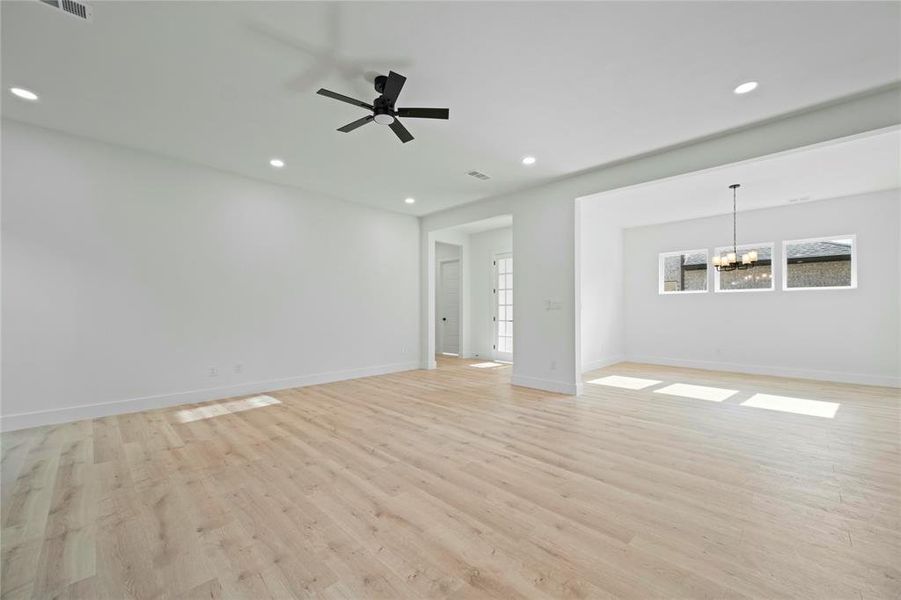 Unfurnished living room with a chandelier, light wood-style floors, recessed lighting, and a ceiling fan