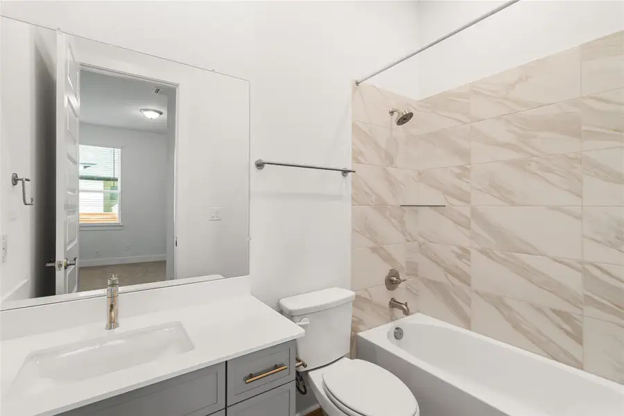 A bathroom features a modern vanity and a tiled shower-tub combination. A bathroom features a modern vanity and a tiled shower-tub combination.