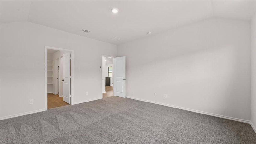 Spacious room featuring vaulted ceilings and neutral gray carpeting