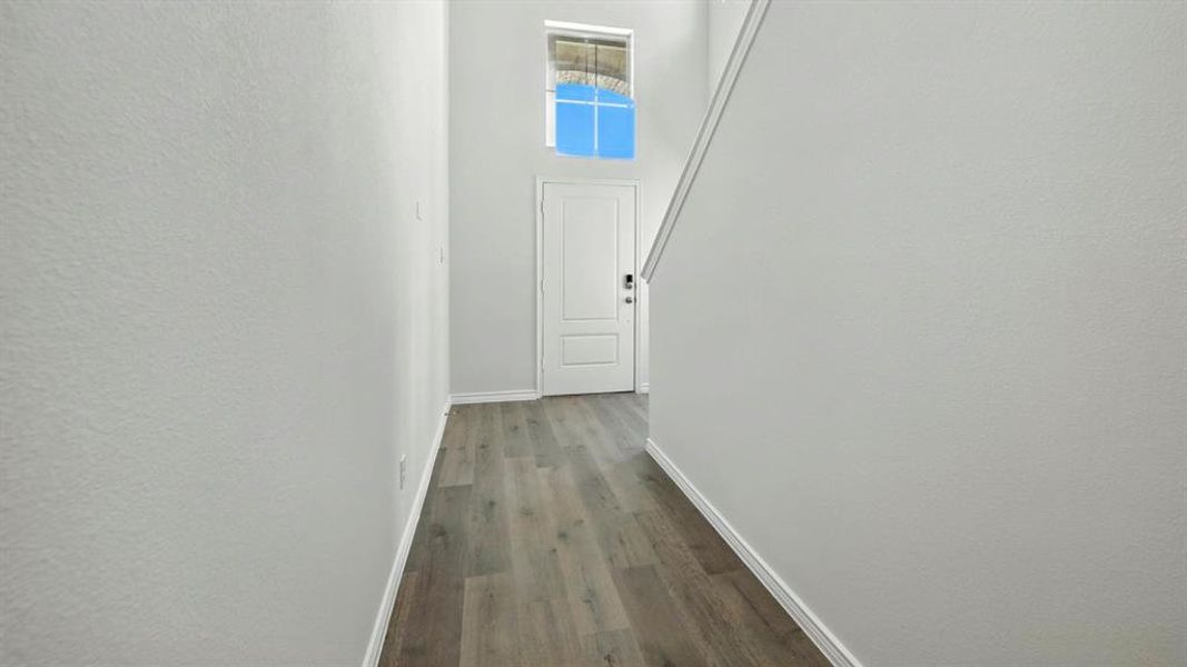 Corridor with dark wood-style flooring, a towering ceiling, and a textured wall