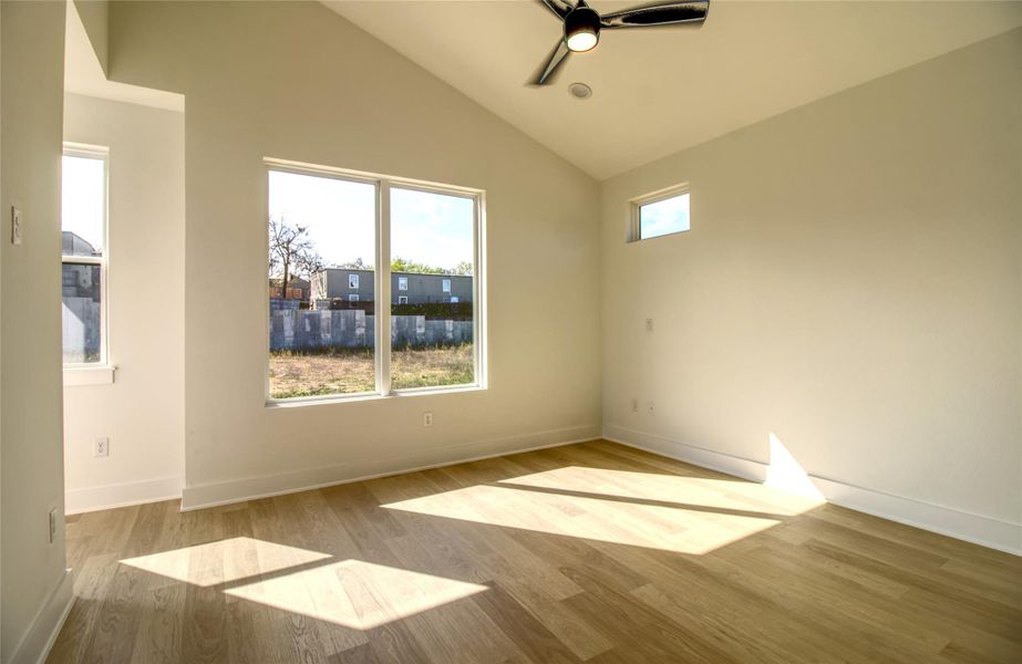 Primary bedroom featuring lofted ceiling, light wood-style floors, and a ceiling fan
