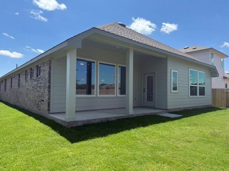 Rear exterior featuring a covered patio, extensive green space, and a combination of brick and horizontal siding